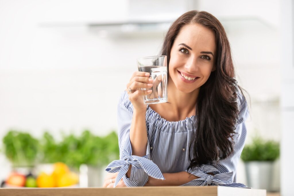 Smiling woman drinking crystal clear water from glass