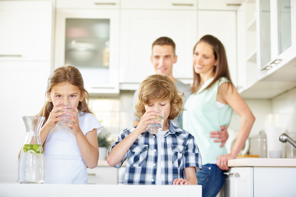 Kids drinking water with parents behind them smiling